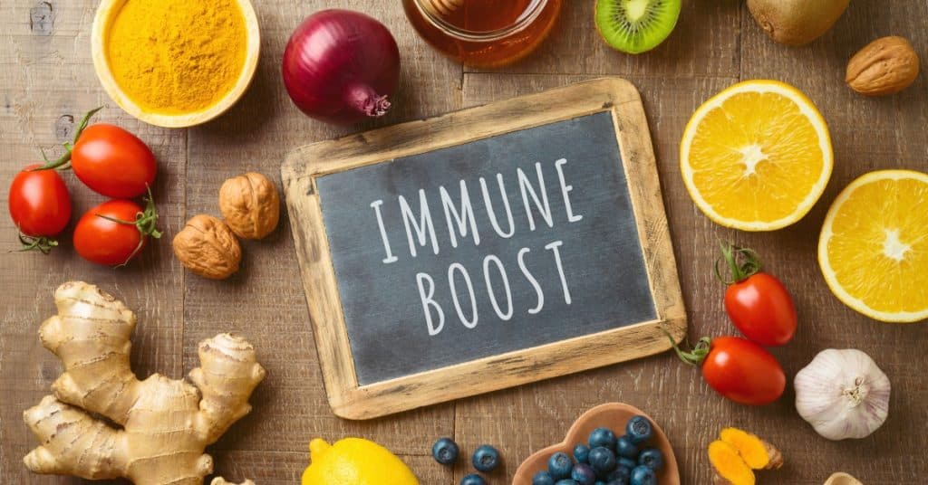 Colorful fruits and vegetables arranged on a table surround a chalkboard with the words 'immune boost' on it.