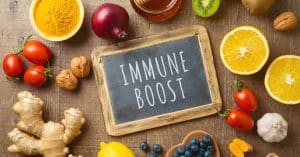 Colorful fruits and vegetables arranged on a table surround a chalkboard with the words 'immune boost' on it.