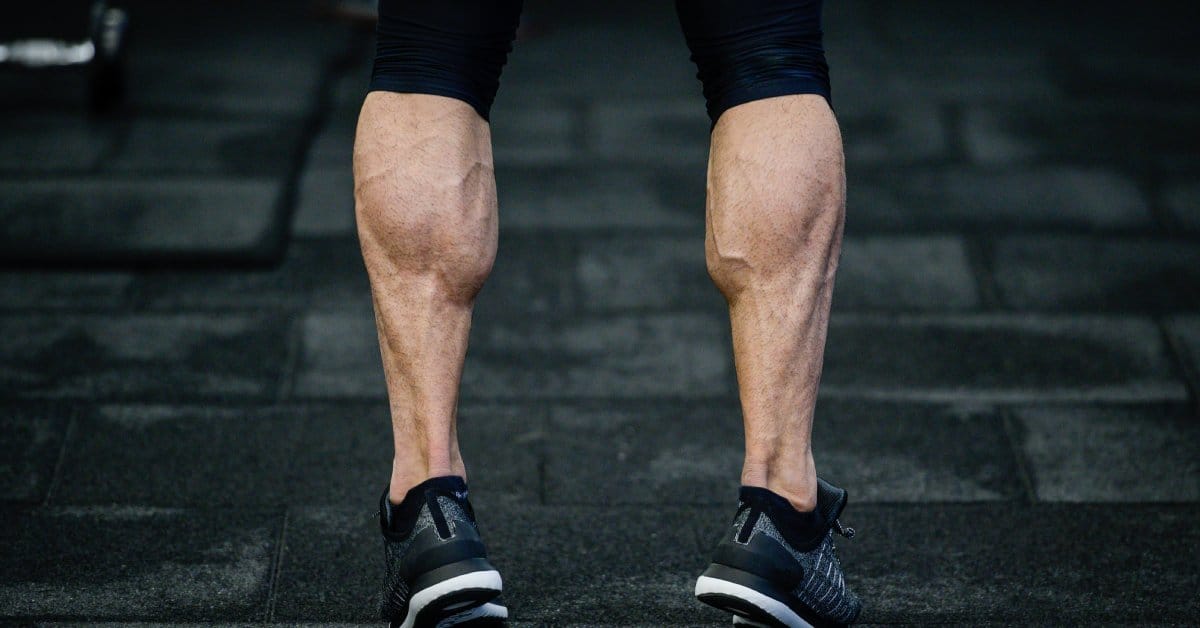 A fit person standing on the toes of their feet to make their large, trained calf muscles protrude more.