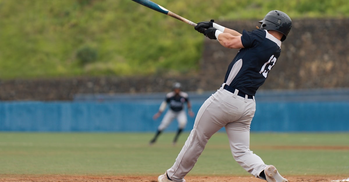 A baseball player wearing a black jersey with the number 13, a helmet, and gray pants swings with a bat right-handed.