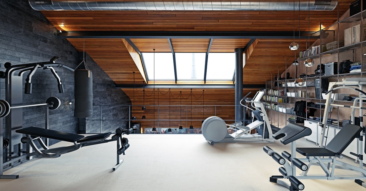 A view of a home gym room in a loft-style attic with modern equipment and storage shelving on the wall.